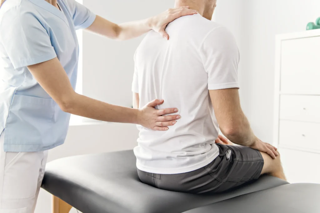a physiotherapist examines their patient's back to determine the source of their back pain