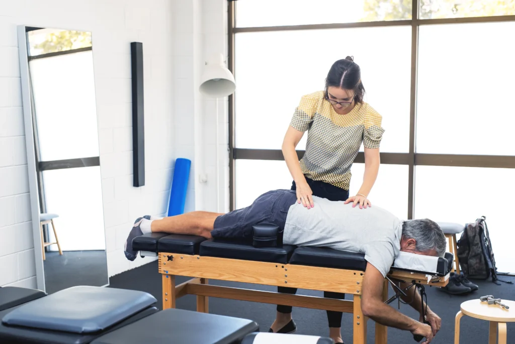a physiotherapist examines her patient's back and administers physiotherapy treatments to treat his back pain