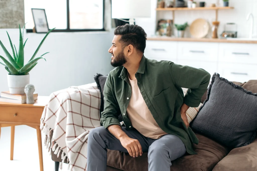 man trying to relax on his couch but his lower back pain keeps him from relaxing